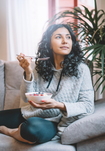 Woman eating yogurt on couch